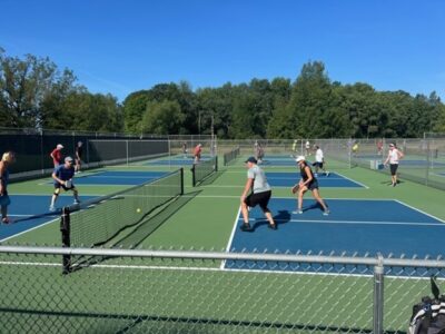 People playing pickleball on a series of pickleball courts.