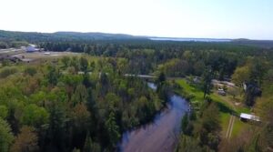 Aerial view of a river winding through a forest in Maley Park in Honor, Michigan.