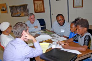Four adults and two children talking at a table