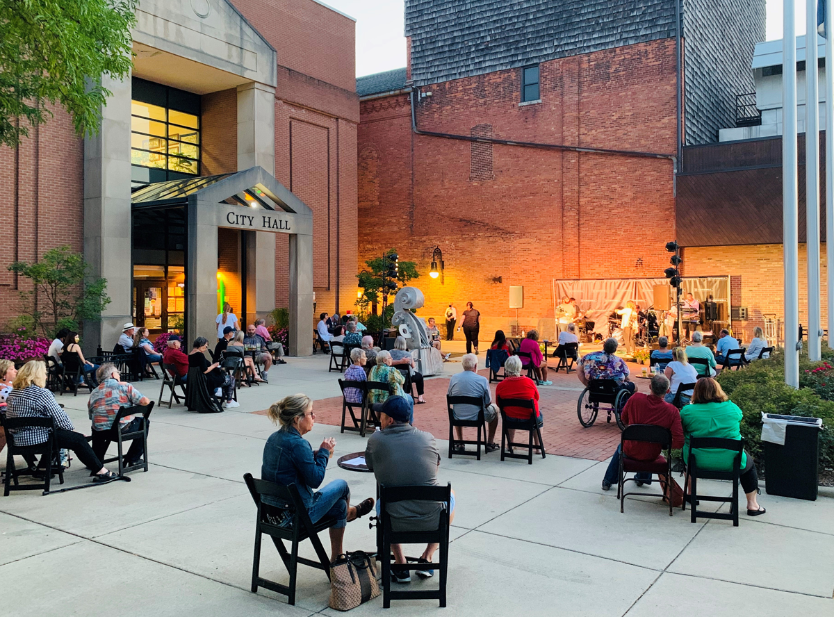 A group of people watching a band perform outside Croswell city hall.