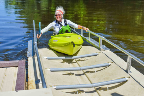 A person launching their kayak into a river.