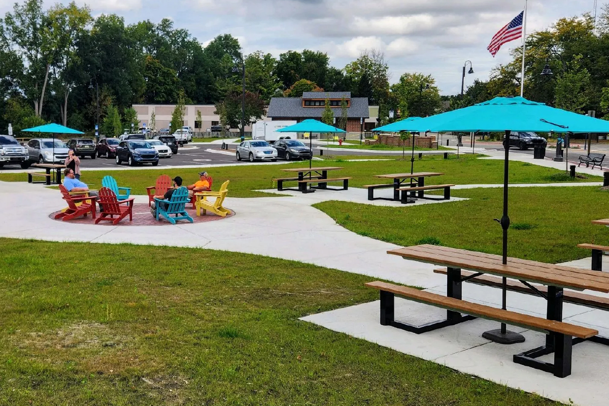 People sitting in colorful chairs on a patio with bright colored umbrellas and picnic tables.