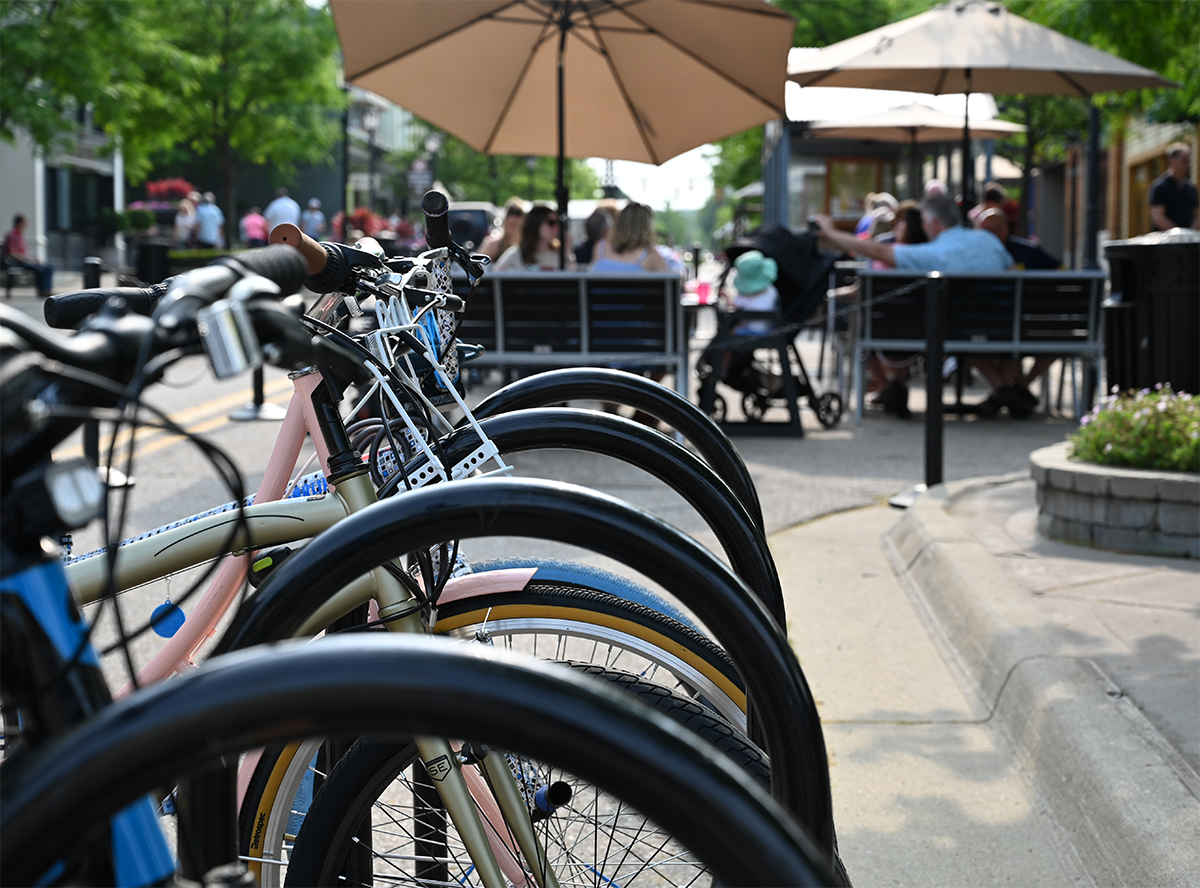 A line of bikes parked near people dining in the street in downtown Northville.