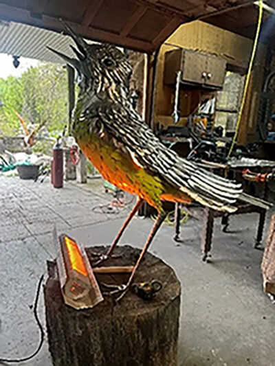 Large sculpture of a warbler being built in a pole barn.