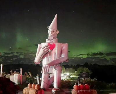 A large sculpture of the Tin Man, from Wizard of Oz, holding a heart. The northern lights are visible along the skyline behind him.