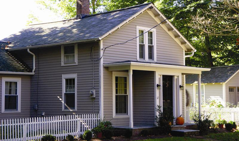 Housing-photo-cover A well kept, two story house, in a city neighborhood, with a white picket fence and a pumpkin on the porch.