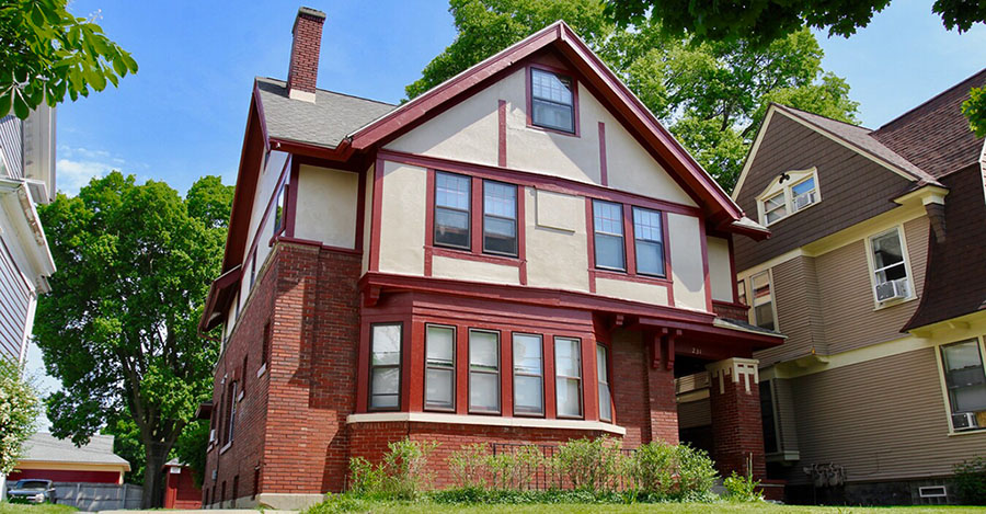 mi-housing-post Brick, red and yellow multilevel house with houses on either side with blue sky.